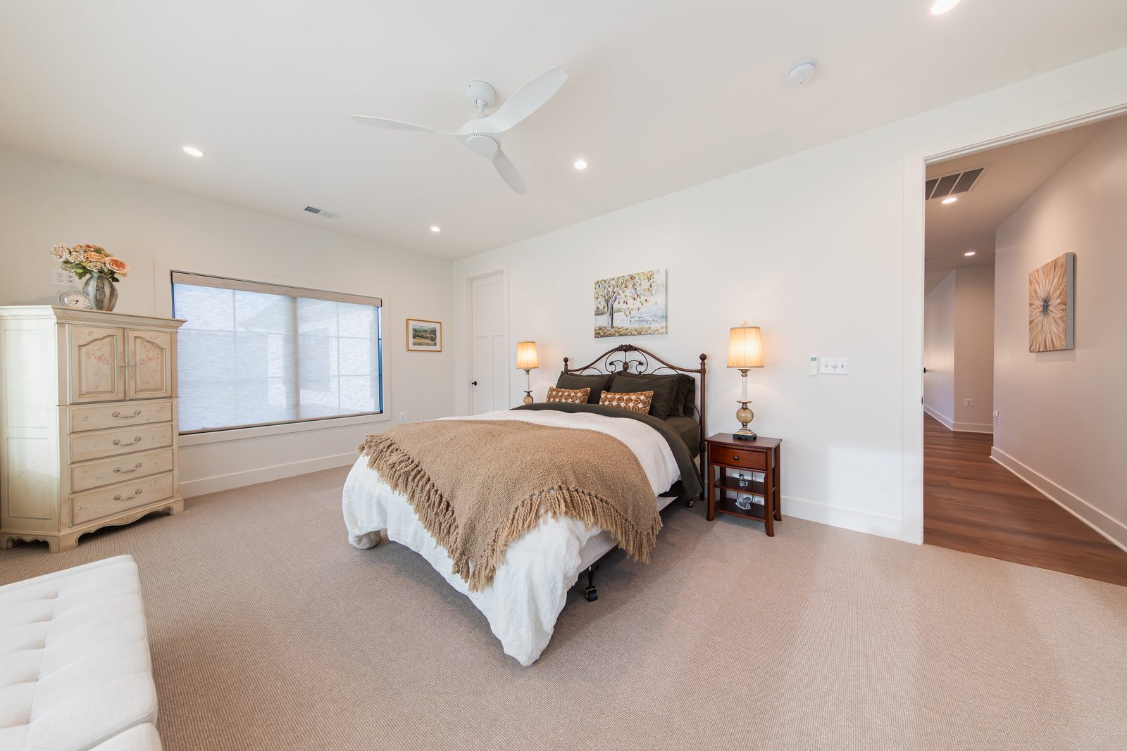 A bedroom with a cream dresser and iron bed