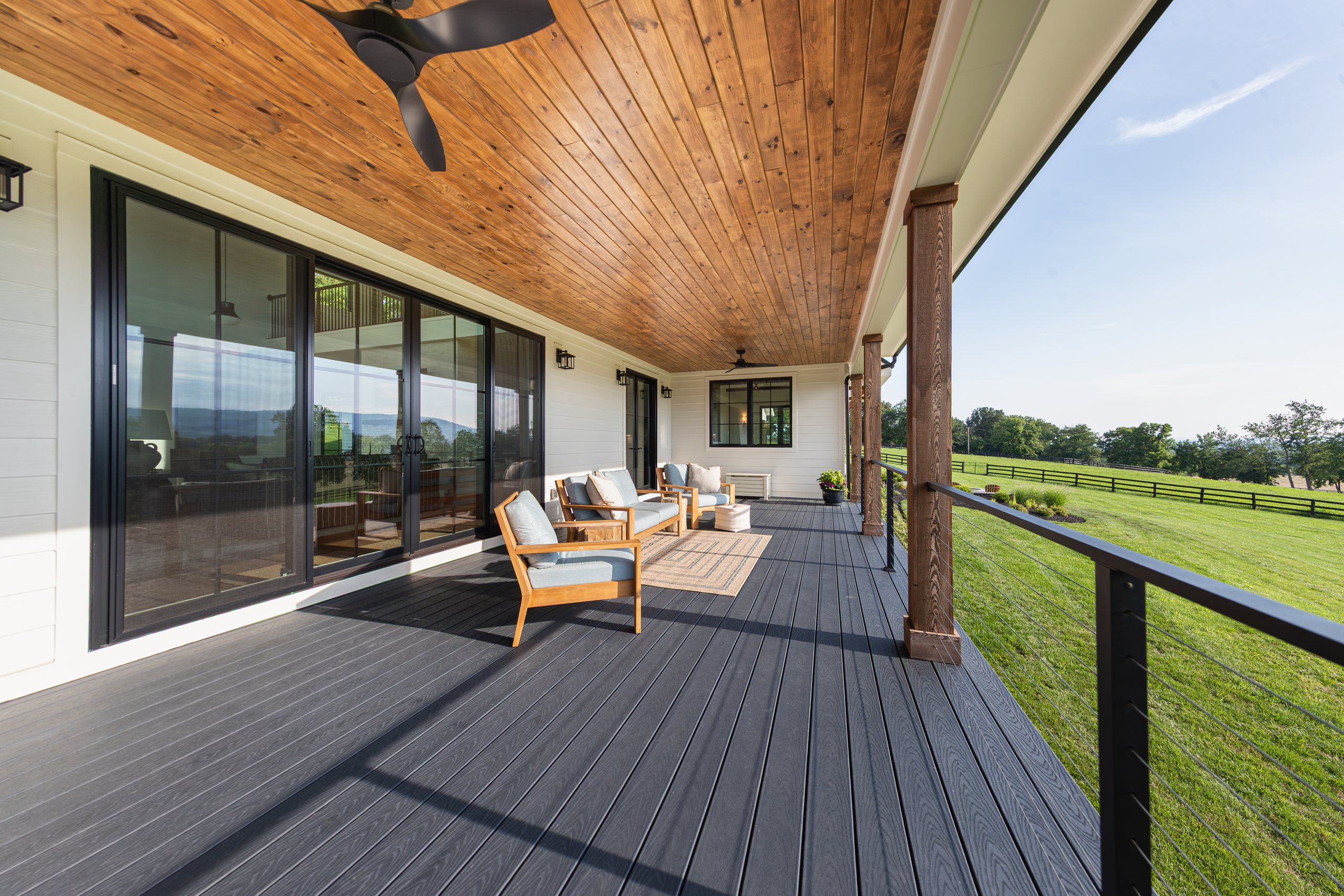 The covered porch of a finished Total Build home, looking out over the fields